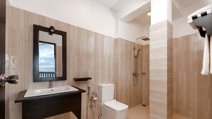 Une salle de bain moderne avec un grand miroir, un lavabo, des toilettes et une douche.