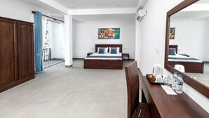 Une chambre d’hôtel avec un grand lit, un bureau avec un miroir, un tableau au mur et une armoire.