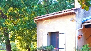 A rustic house with a stone wall, a small garden with a fountain, and a red toy truck. - THE PROVENCE (Bollène)