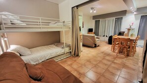 Une pièce avec des lits superposés, un canapé, une table à manger avec des chaises et un téléviseur.