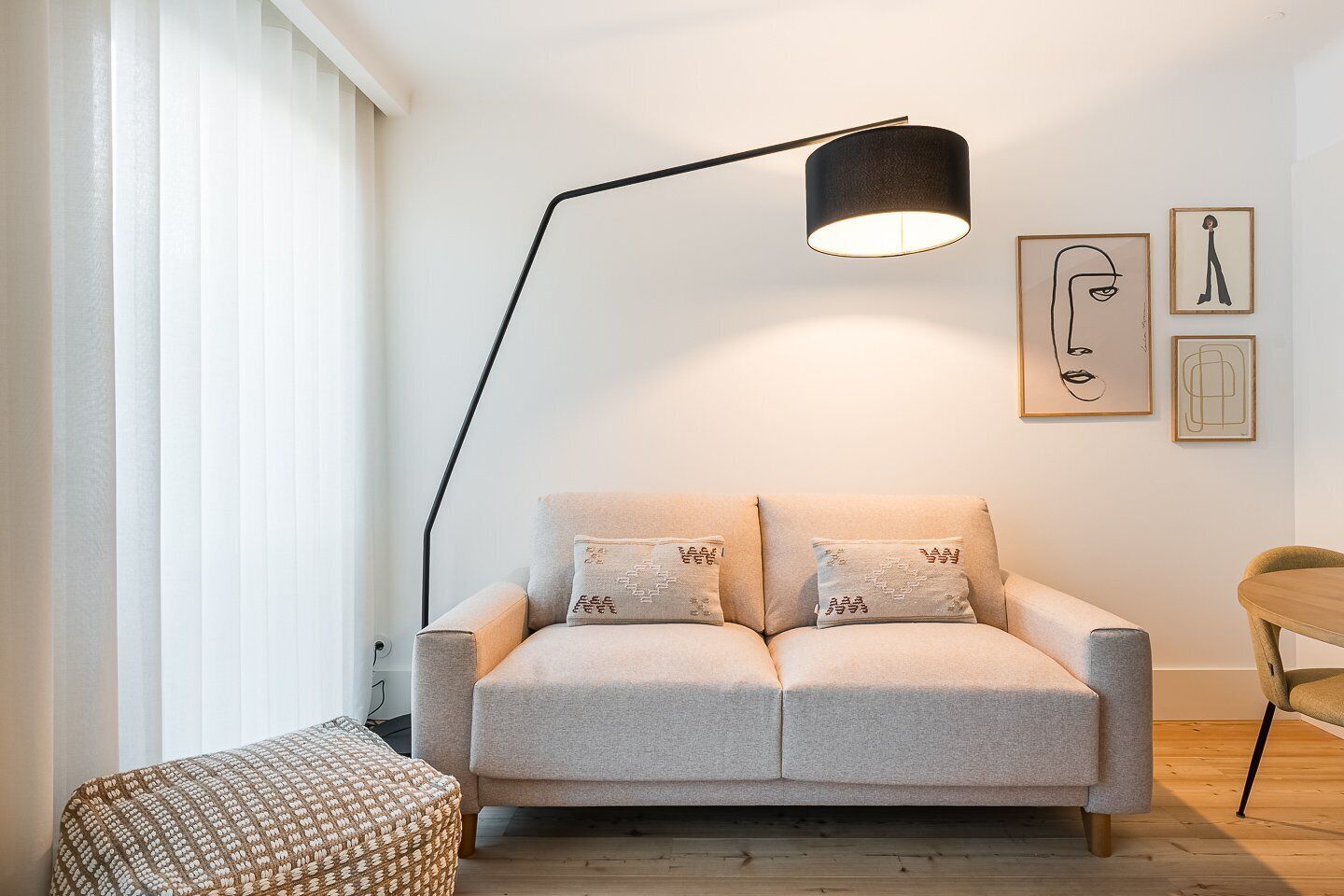 Ein modernes Wohnzimmer mit einer Couch, einer Stehlampe, einem kleinen Tisch und Bildern an der Wand.