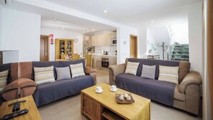 A modern living room with two sofas, a wooden coffee table, and a kitchen in the background. - Villa Sol - Two Bedroom Villa, Sleeps 4 (Puerto del Carmen)