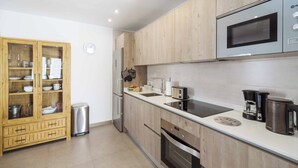 A modern kitchen with wooden cabinets, stainless steel appliances, and a built-in microwave. - Villa Sol - Two Bedroom Villa, Sleeps 4 (Puerto del Carmen)
