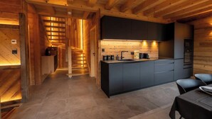 A modern kitchen with a central island, dark cabinetry, and a wooden ceiling.