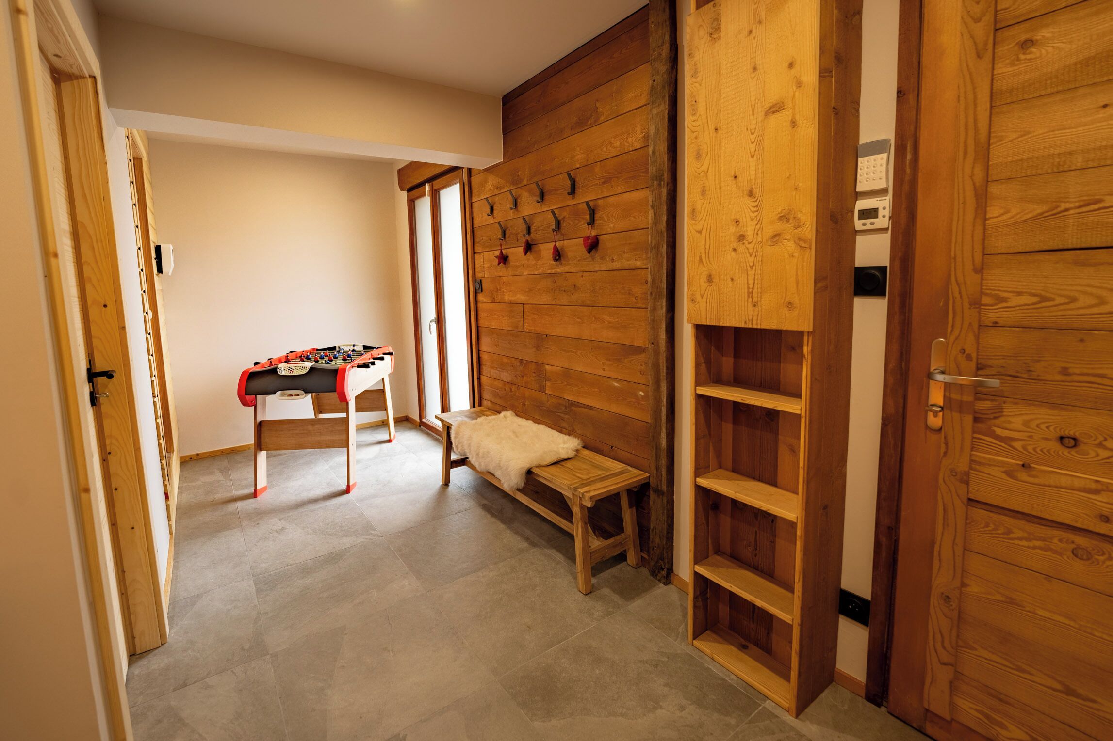 Ein Zimmer mit einer Holzwand, einer Bank, einem kleinen Tisch mit einem roten und weißen Gegenstand und einer Tür mit Griff.