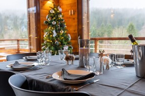 A dining table set for four with a Christmas tree in the background. - Chalet Les Cimes - Sauna - Jacuzzi (Gérardmer)