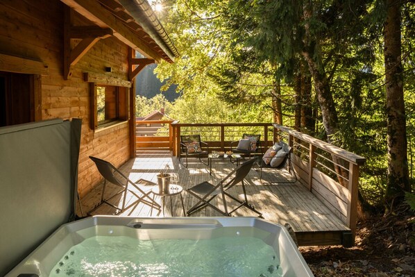 A wooden cabin with a hot tub, deck chairs, and a view of the forest. - Chalet Les Cimes - Sauna - Jacuzzi (Gérardmer)