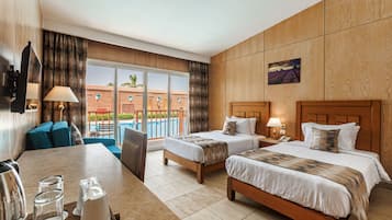 A hotel room with two beds, a dining table, and a view of a pool and buildings.