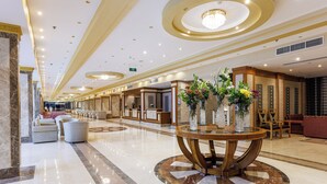 A spacious lobby with a marble floor, a reception desk, and a seating area with sofas and a round table with vases. - SUNRISE Solara Aqua park Resort (Hurghada)