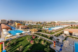 Un resort con varias piscinas, tumbonas y un jardín bien cuidado.