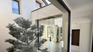 Un intérieur moderne avec une cloison en verre, un petit arbre artificiel et un sol carrelé.