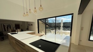 Una cocina moderna con una isla grande, un comedor con asientos exteriores y vistas al exterior.