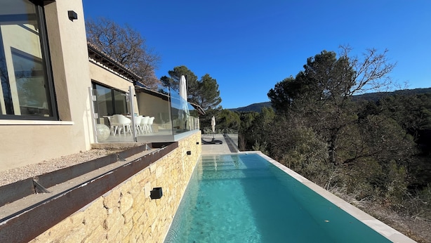 Une maison moderne dotée d’une piscine, d’un escalier en pierre et d’un espace salon extérieur.