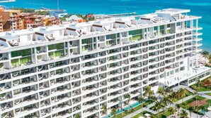 Un hotel de varios pisos con balcones, una zona de piscina y vista al océano.