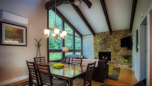 A dining area with a wooden table and chairs, a chandelier, and a stone fireplace. - 3-Bedroom 2 Bath Cozy Chalet 1 Mile From Mountain! (Lanesville)