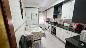 Une cuisine compacte comprenant un coin repas, un lave-linge, une cuisinière et un réfrigérateur.