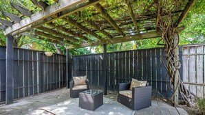 Uma área de varanda coberta com móveis de vime e uma pérgola.