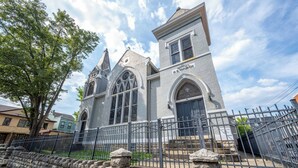 Igreja com muro de pedra e grade de metal na frente.