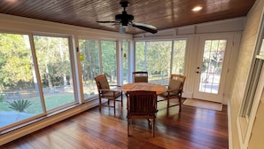 A spacious room with wooden flooring, a ceiling fan, and large windows offering a view of the outdoors. - Peach Jam Luxury Gentleman's Retreat ~ 5 BR BA One of a kind find! (North Augusta)