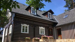 A traditional wooden house with a stone wall, two windows with shutters, and a wooden bench in the foreground. - Chalet in Liberec Near Ski Resort Jested (Svetla pod Jestedem)