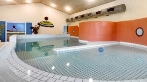 An indoor swimming pool with a tiled floor, a ceiling with recessed lighting, and a wall with a large circular window. - 5 Star Holiday Home in Lokken (Lokken)