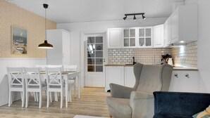 A modern kitchen with white cabinets, a tiled backsplash, and a dining area with white chairs. - 5 Star Holiday Home in Lokken (Lokken)