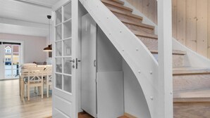 A modern interior with a wooden staircase, a white door leading to a dining area, and a visible kitchen. - 5 Star Holiday Home in Lokken (Lokken)