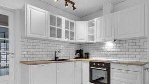 A modern kitchen with white cabinetry, a black stove, and a wooden countertop. - 5 Star Holiday Home in Lokken (Lokken)