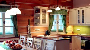A cozy kitchen with wooden walls, white cabinets, and a central island. There are hanging lights, a window with curtains, and a sink. - Villa Near Horni Domky Ski Resort (Rokytnice nad Jizerou)