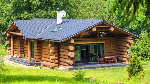 A log cabin with a sloped roof, a satellite dish, and a patio with outdoor furniture. - Villa in Lomnice nad Popelkou (Lomnice nad Popelkou)