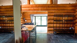 A log cabin with a dining area, metal chairs, a table, and a view through a glass door. - Villa in Lomnice nad Popelkou (Lomnice nad Popelkou)