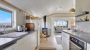 Een moderne keuken met witte kasten, een inbouwoven en een groot raam.