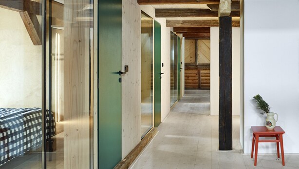 Een modern interieur met een houten plafond, glazen deuren en een gang die leidt naar een slaapkamer.