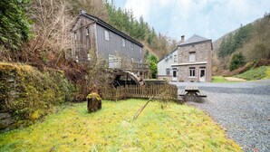 A rustic building with a wooden exterior, a stone house, and a gravel driveway. - Historic Watermill in Bohan (Vresse-sur-Semois)