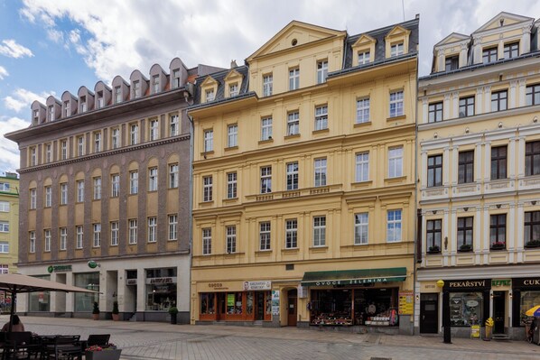 A row of historic buildings with ground-floor shops, including a pharmacy and a jewelry store.