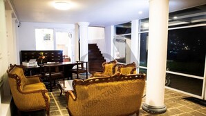 Un vaste espace de vie comprenant un canapé, des fauteuils et une table basse. Un escalier mène à l’étage supérieur.