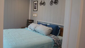A bedroom with a bed, pillows, a headboard, a wall-mounted bicycle decoration, and a framed picture. - Charming 2 bedroom home in Tallassee, Alabama near Lake Martin (Tallassee)