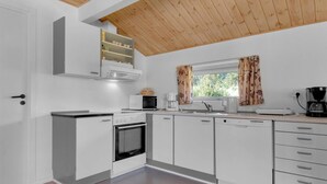 A modern kitchen with white cabinets, a built-in oven, a microwave, and a coffee maker. - 5 Star Holiday Home in Blokhus (Blokhus)
