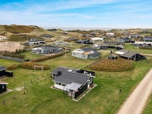 A coastal residential area with multiple houses, some with attached garages, and a clear view of the sea in the background. - 5 Star Holiday Home in Lokken (Lokken)