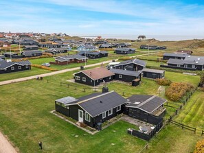 A residential area with multiple houses, some with attached garages, and a clear view of the sea in the background. - 5 Star Holiday Home in Lokken (Lokken)