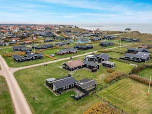 A residential area with multiple houses, a clear sky, and a body of water in the background. - 5 Star Holiday Home in Lokken (Lokken)