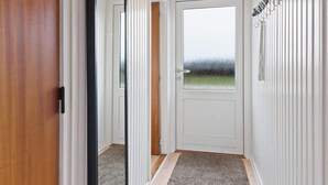 A hallway with a white door, a wooden door frame, and a coat rack with hangers. - 5 Star Holiday Home in Lokken (Lokken)