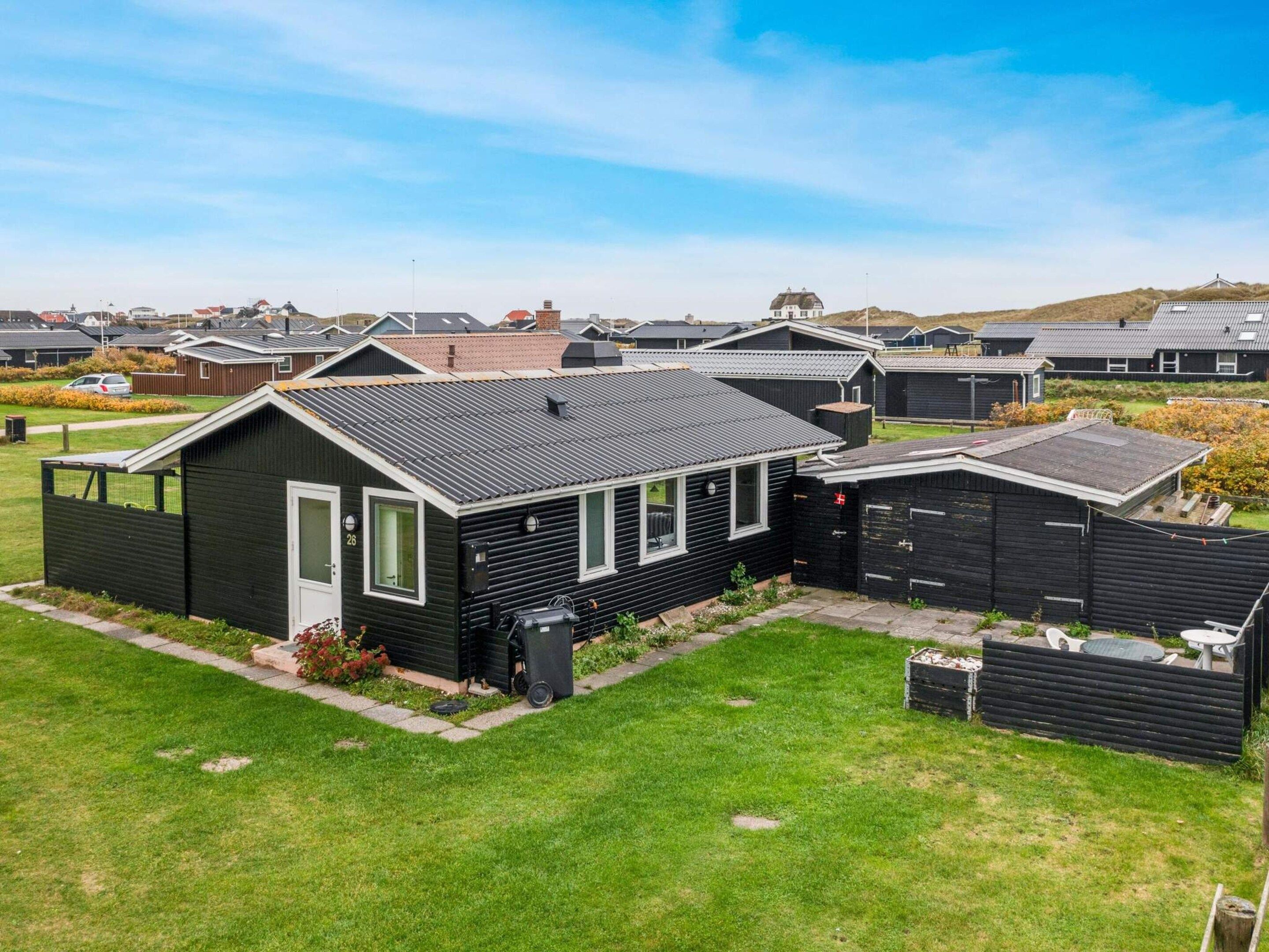 A row of modern, black-roofed mobile homes with a well-maintained lawn and a clear sky.