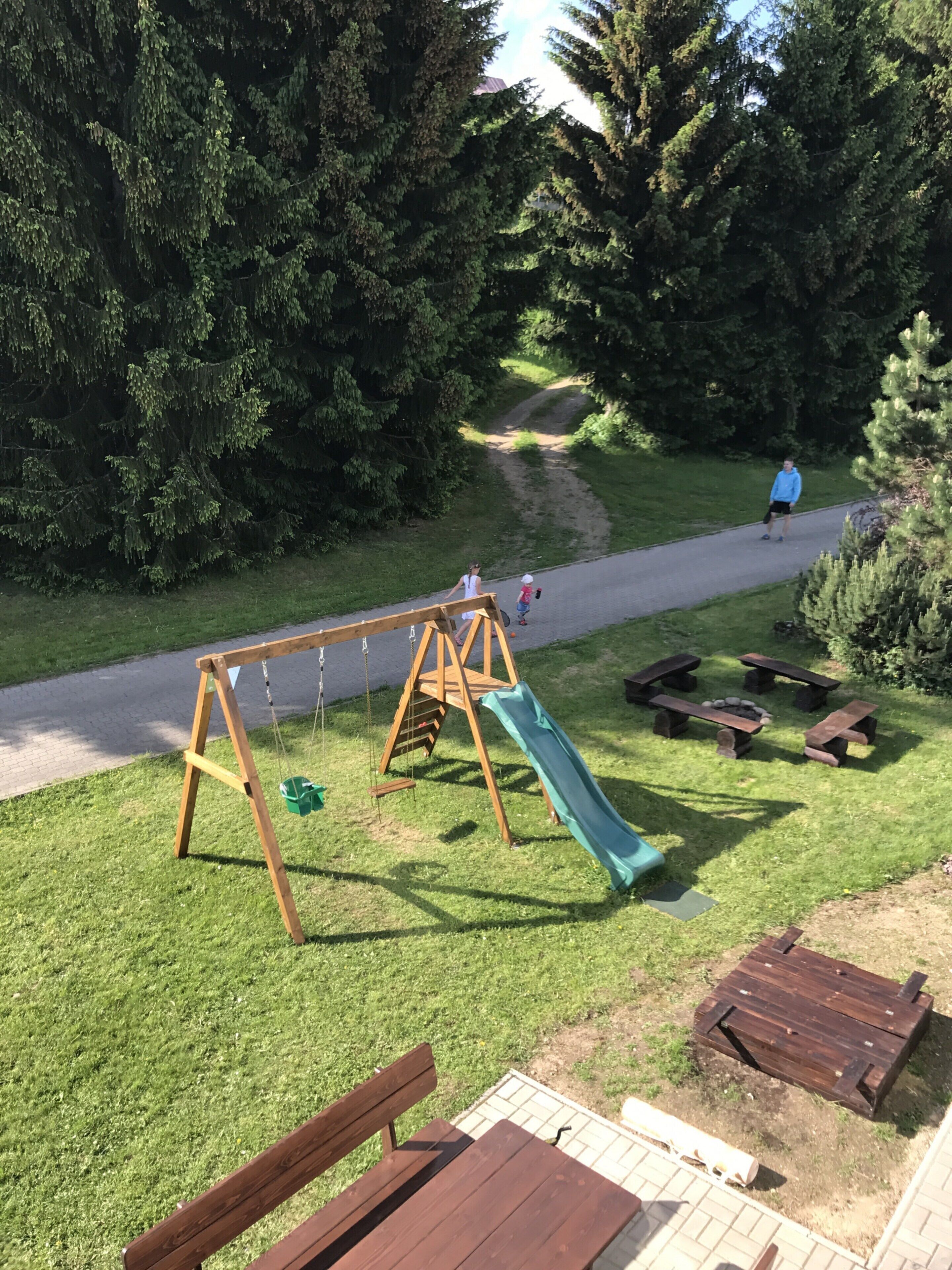 A playground with a swing set, slide, and picnic tables.