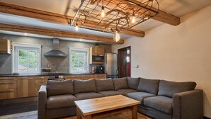 A modern living room with a sectional sofa, a wooden coffee table, and a kitchen in the background. - Chalet in Horni Marsov Near Ski Slopes (Horni Marsov)