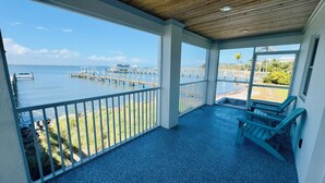 A covered balcony with a view of a marina and the sea.