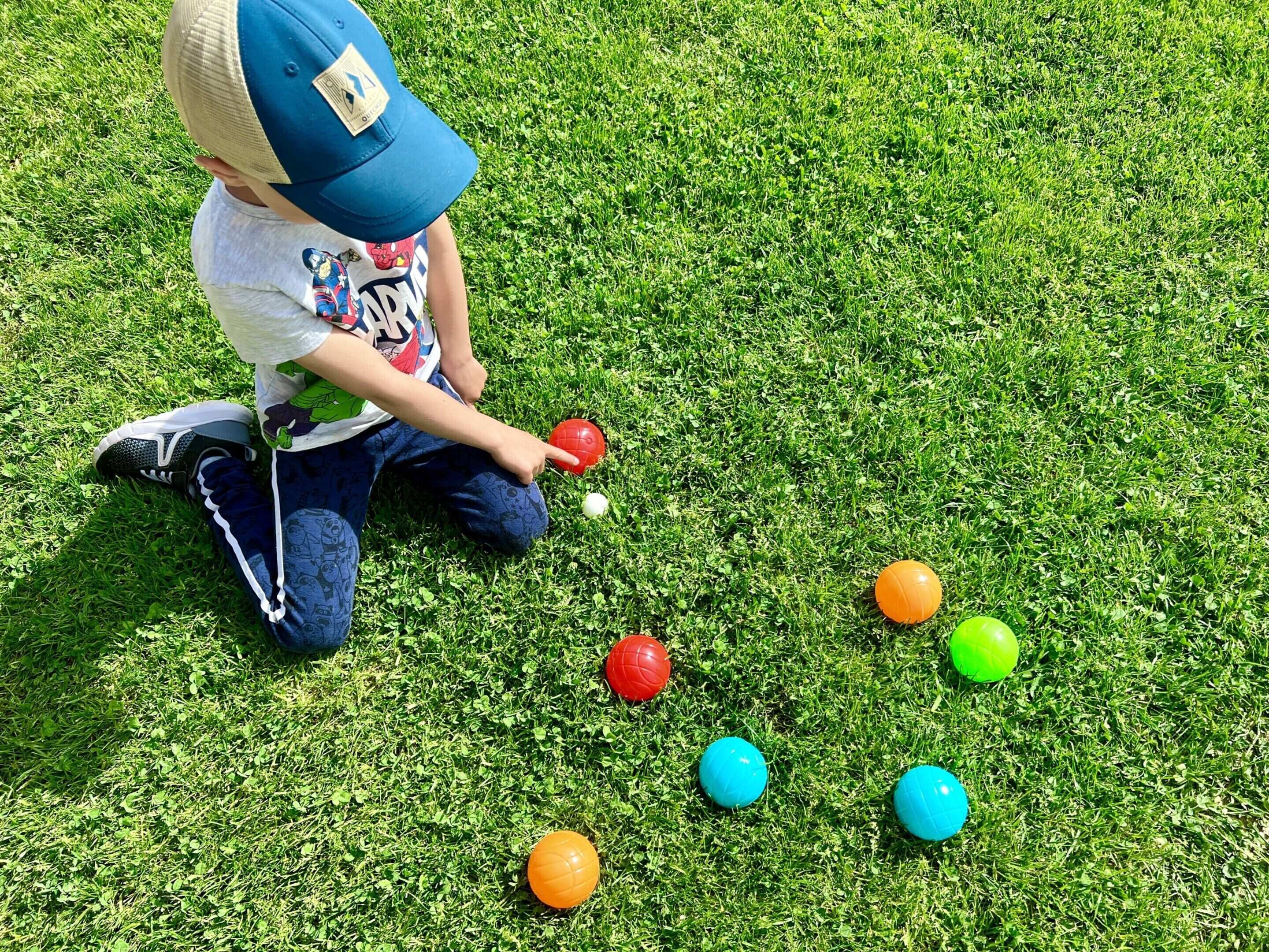 Un bambino gioca con delle palle colorate su un prato.