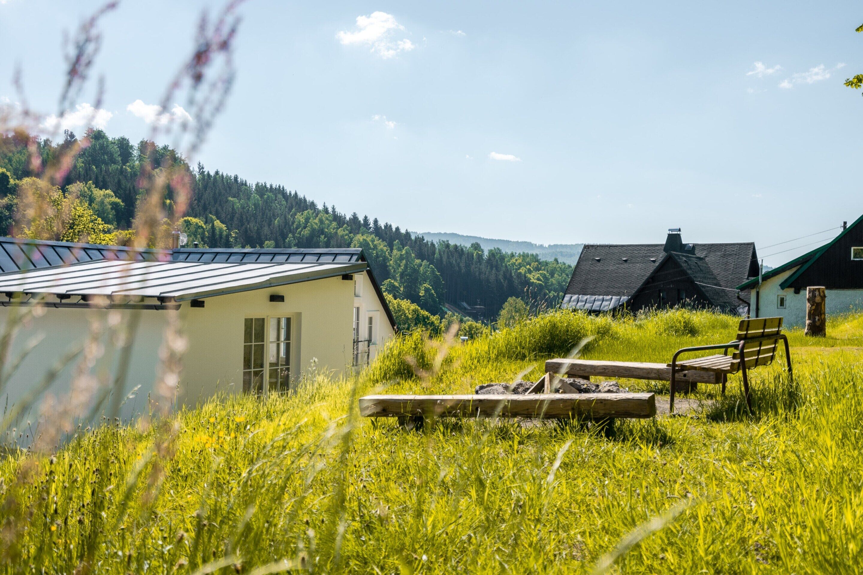 A rural setting with a house, a bench, and a wooden platform.