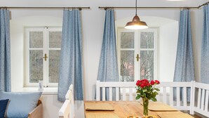 Ein gemütlicher Essbereich mit einem Holztisch, gewebten Untersetzern und einer Vase mit roten Rosen.