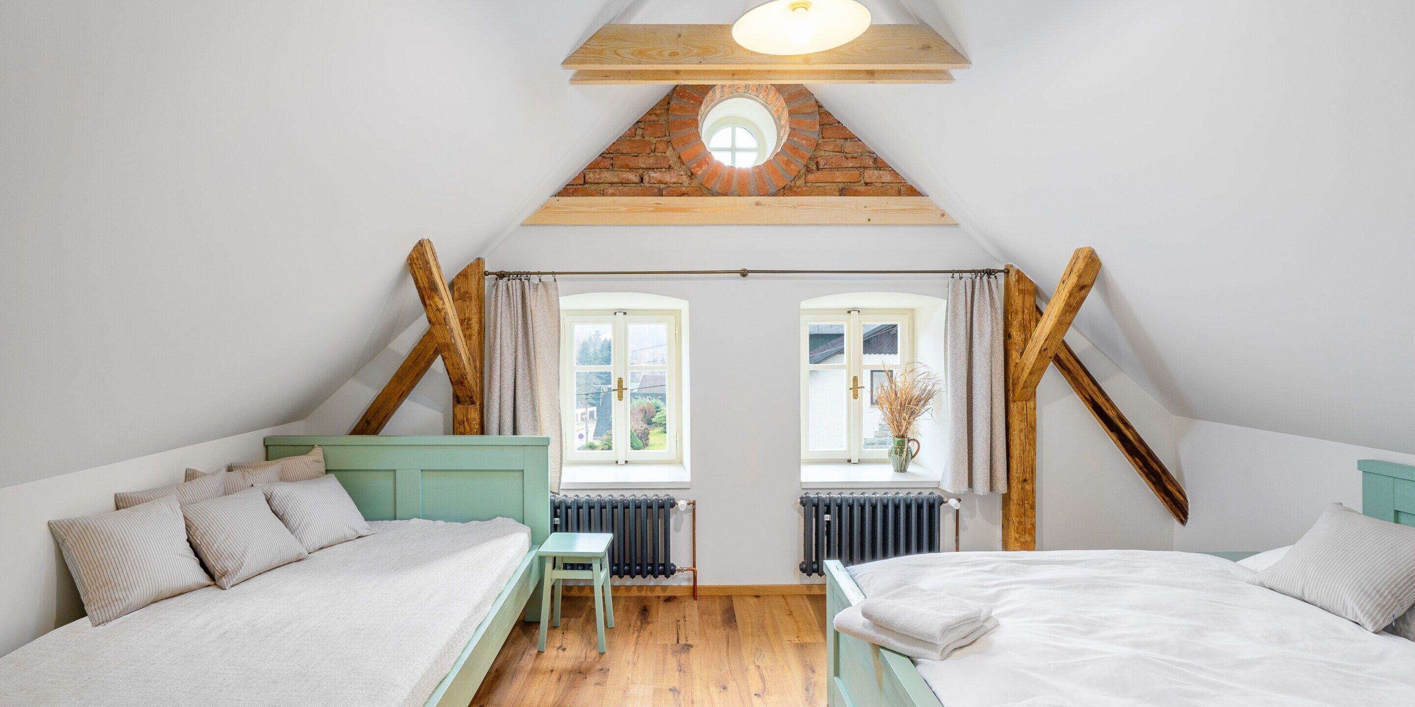 A bedroom with two beds, a small table, and a window with curtains.